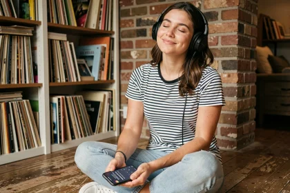 Jeune femme française écoutant de la musique anglaise au casque dans un appartement parisien avec des vinyles en arrière-plan